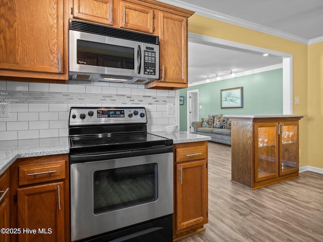 kitchen featuring tasteful backsplash, stainless steel appliances, crown molding, and light stone countertops