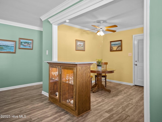 bar featuring hardwood / wood-style flooring, ornamental molding, and ceiling fan