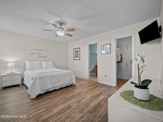 bedroom with a walk in closet, a textured ceiling, dark hardwood / wood-style floors, a closet, and ceiling fan