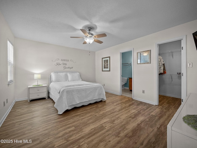 bedroom with ensuite bathroom, hardwood / wood-style floors, a walk in closet, ceiling fan, and a closet