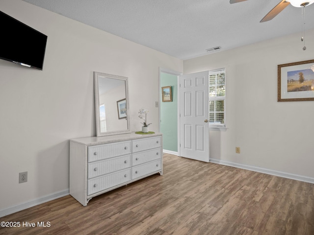 bedroom with a textured ceiling, wood-type flooring, and ceiling fan