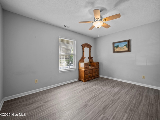 unfurnished bedroom with ceiling fan, wood-type flooring, and a textured ceiling