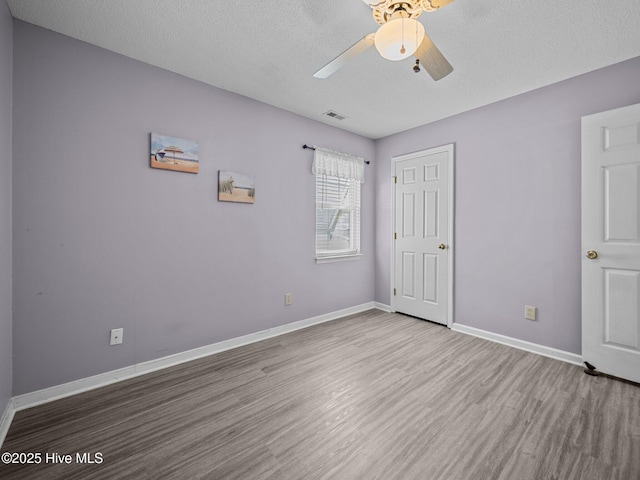 unfurnished bedroom featuring hardwood / wood-style flooring, a textured ceiling, and ceiling fan