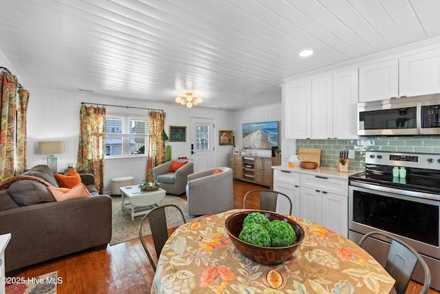 kitchen featuring stainless steel appliances, dark hardwood / wood-style flooring, white cabinets, and tasteful backsplash