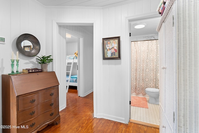 hallway featuring hardwood / wood-style flooring, wood walls, and crown molding