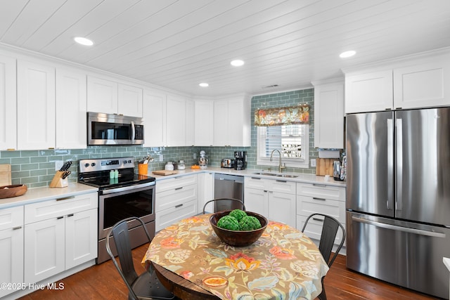 kitchen with stainless steel appliances, decorative backsplash, white cabinetry, and sink