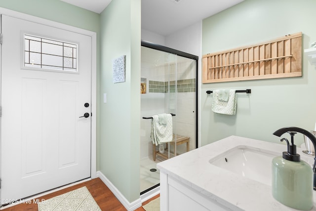 bathroom with vanity, hardwood / wood-style flooring, and a shower with door