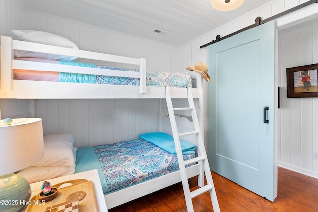 bedroom with hardwood / wood-style flooring and a barn door