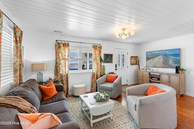 living room with light hardwood / wood-style floors, wooden ceiling, and a notable chandelier