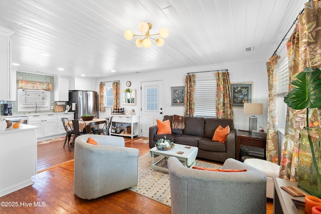 living room with wood-type flooring, sink, an inviting chandelier, and wooden ceiling