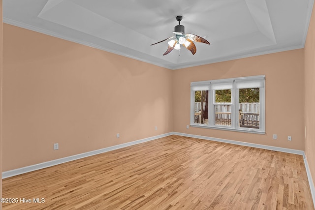 unfurnished room with crown molding, a raised ceiling, ceiling fan, and light wood-type flooring