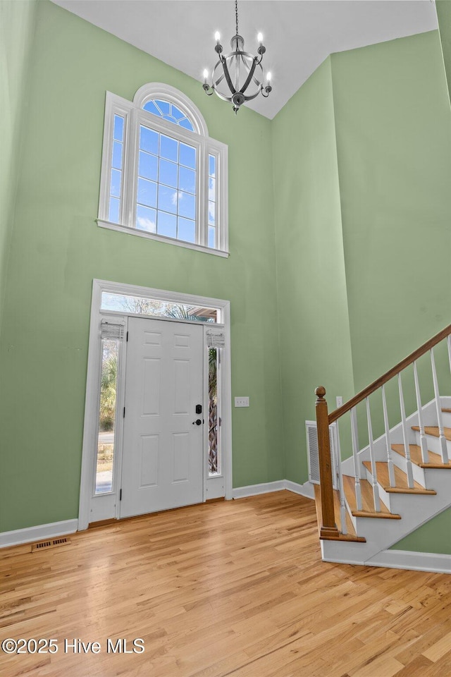 foyer entrance with a wealth of natural light, light hardwood / wood-style flooring, and a high ceiling