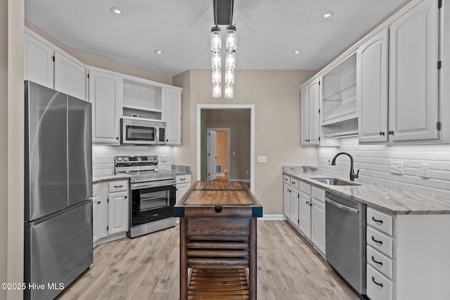 kitchen with sink, white cabinetry, stainless steel appliances, light stone counters, and decorative light fixtures