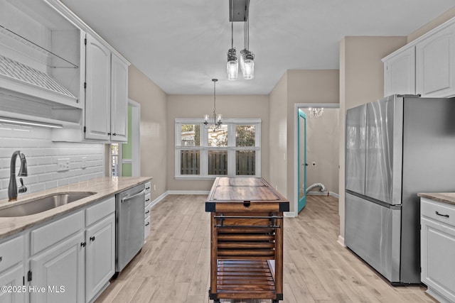 kitchen with sink, appliances with stainless steel finishes, white cabinets, decorative light fixtures, and a chandelier