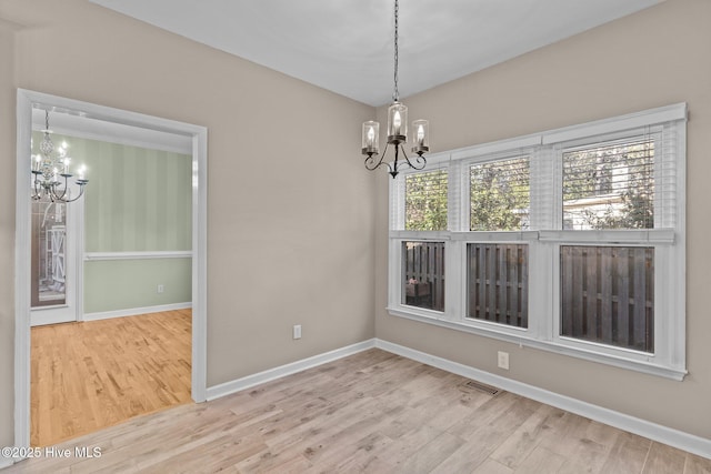 unfurnished dining area featuring a notable chandelier and light hardwood / wood-style floors