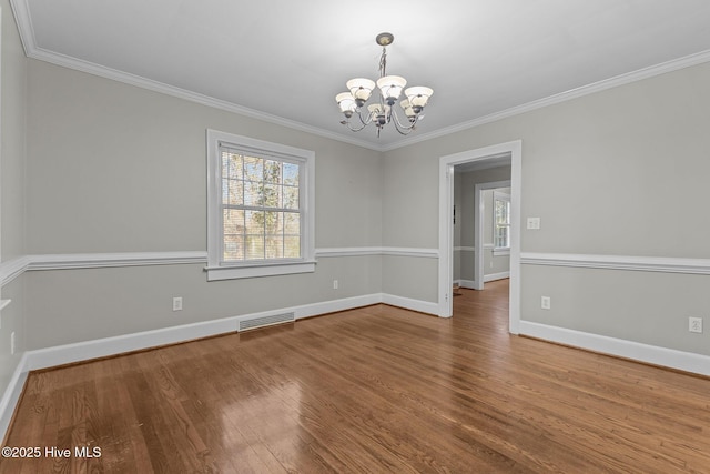 empty room featuring ornamental molding, hardwood / wood-style floors, and a chandelier