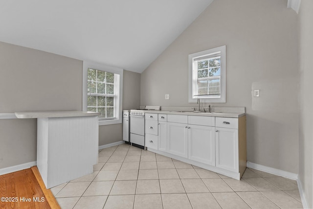 kitchen with white cabinetry, lofted ceiling, sink, kitchen peninsula, and electric stove