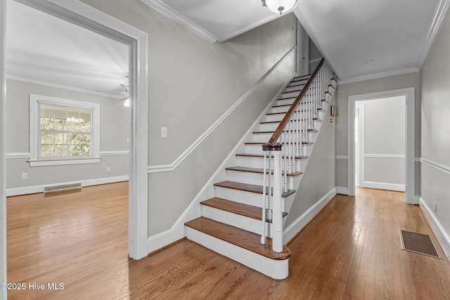 stairway with ornamental molding and wood-type flooring