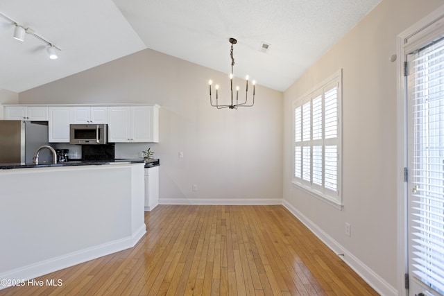 kitchen featuring light hardwood / wood-style floors, tasteful backsplash, hanging light fixtures, white cabinets, and stainless steel appliances