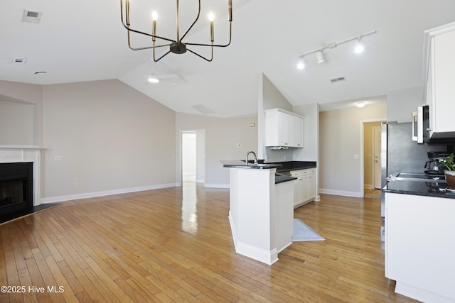 kitchen with light wood-type flooring, white cabinetry, and lofted ceiling