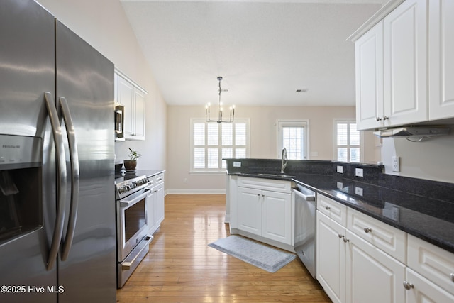 kitchen featuring light hardwood / wood-style flooring, appliances with stainless steel finishes, sink, white cabinets, and dark stone countertops