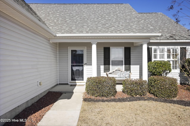 entrance to property with a porch and roof with shingles