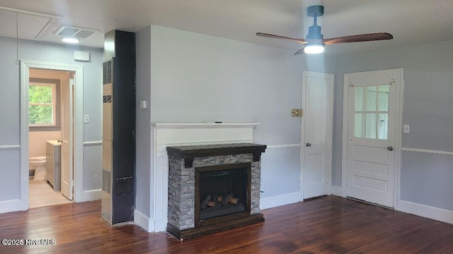 unfurnished living room with ceiling fan, a stone fireplace, and dark hardwood / wood-style flooring