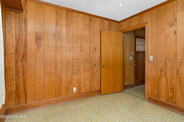 empty room featuring crown molding and wood walls