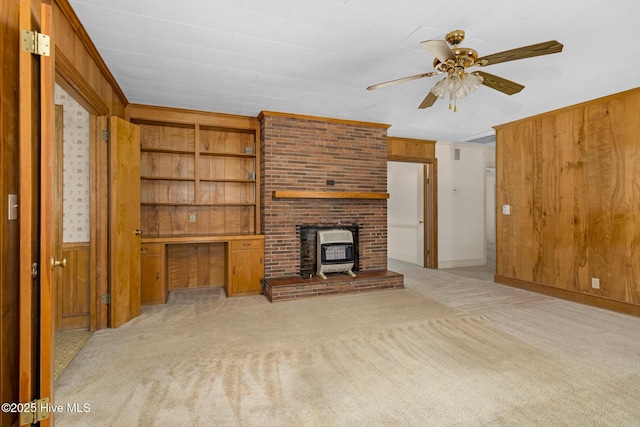 unfurnished living room featuring light colored carpet, built in features, wood walls, and built in desk