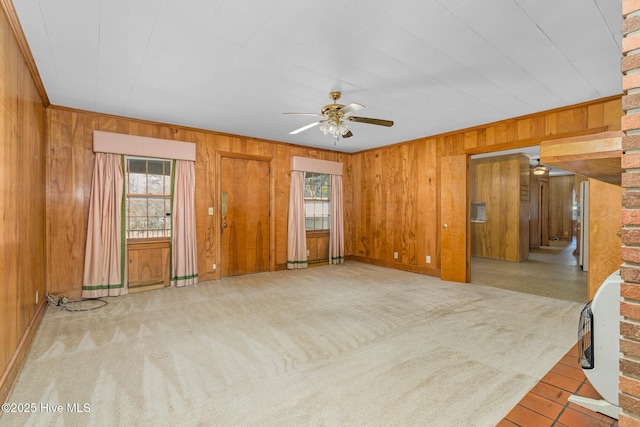 unfurnished living room with a healthy amount of sunlight, light colored carpet, and wood walls