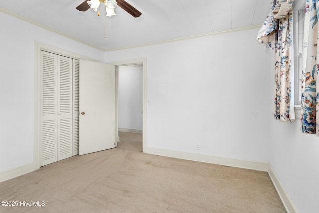 unfurnished bedroom featuring light carpet, ceiling fan, a closet, and crown molding