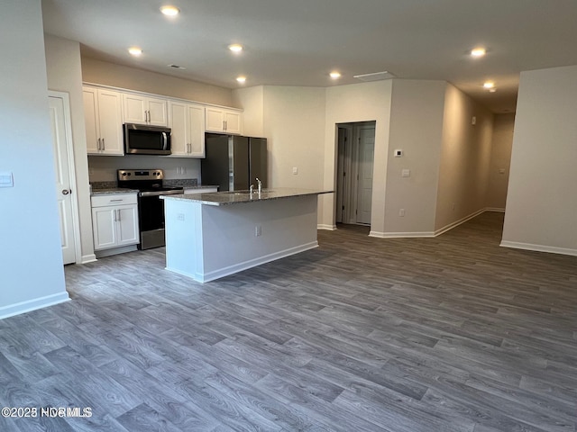 kitchen with white cabinetry, appliances with stainless steel finishes, a center island with sink, and dark hardwood / wood-style flooring