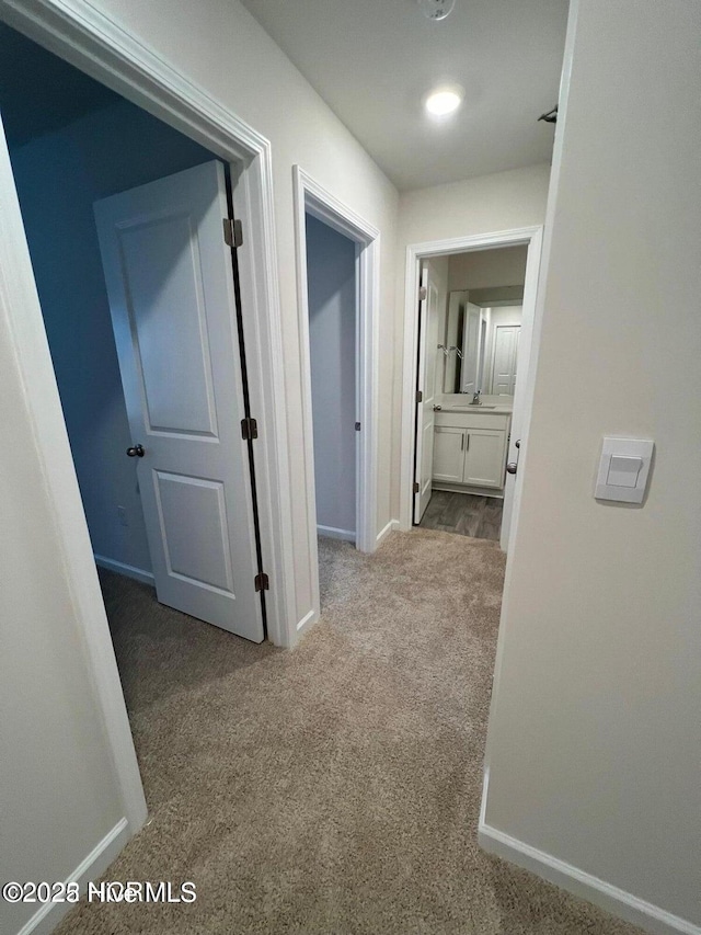 hall featuring light colored carpet and sink