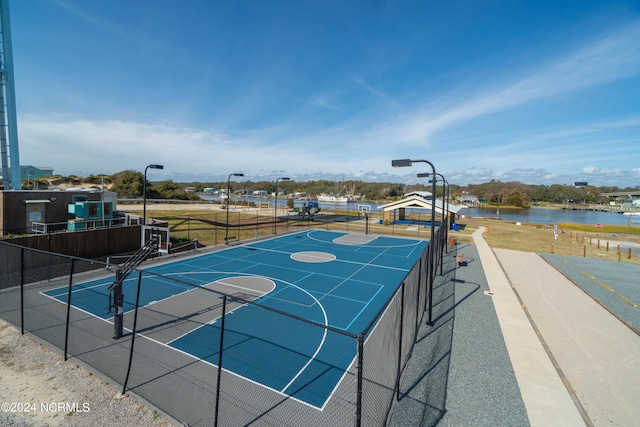 view of basketball court with a tennis court, community basketball court, a water view, and fence