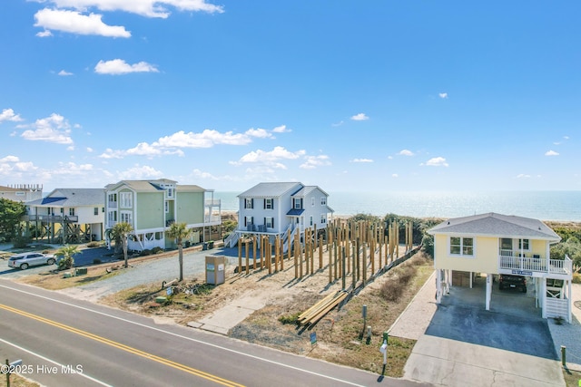 view of front of house with a carport, a residential view, concrete driveway, and a water view