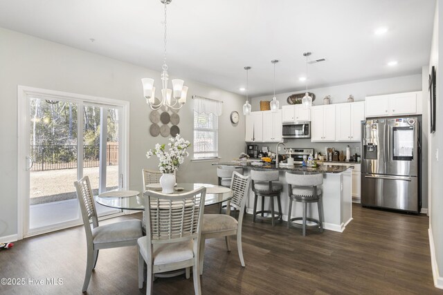 dining area with dark wood-type flooring and an inviting chandelier