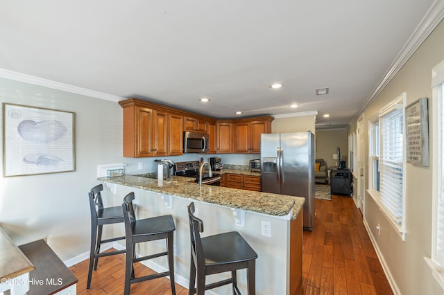 kitchen with kitchen peninsula, stainless steel appliances, dark wood-type flooring, ornamental molding, and light stone counters