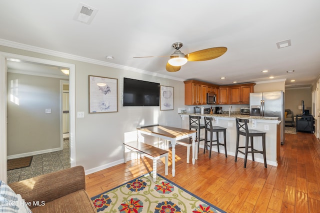 kitchen with a breakfast bar, crown molding, light hardwood / wood-style flooring, and stainless steel appliances