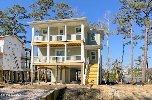 coastal inspired home with driveway, a carport, stairs, a porch, and board and batten siding