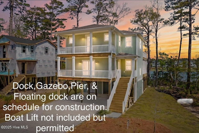 rear view of property featuring a porch, stairs, and a balcony