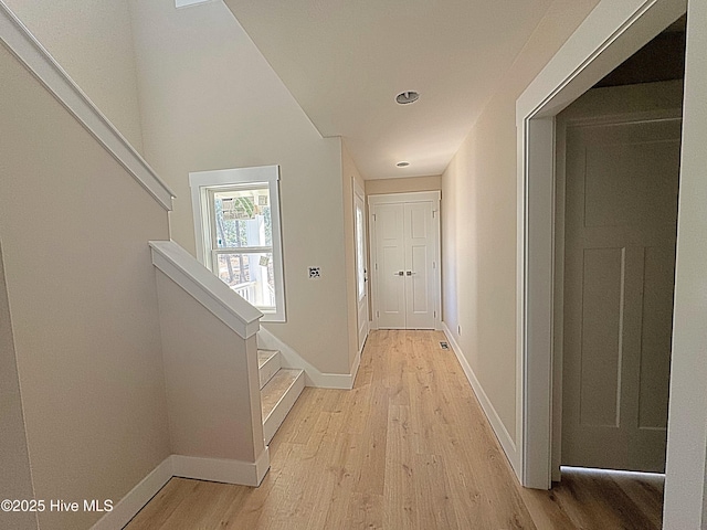 corridor featuring light wood-style floors, stairway, and baseboards