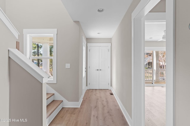 corridor featuring light wood-style floors, baseboards, visible vents, and stairway
