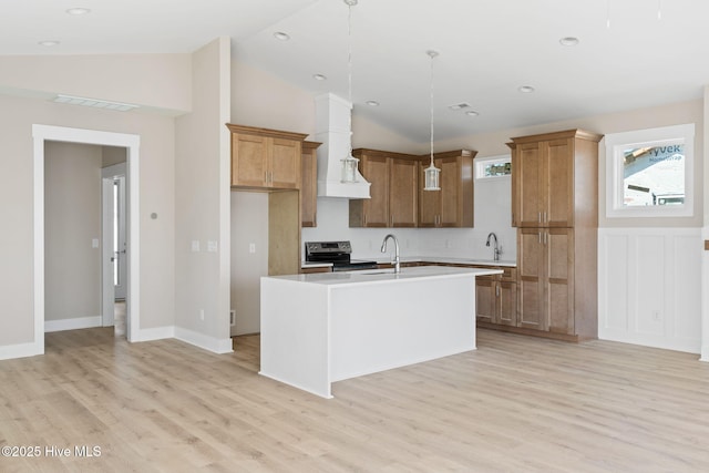 kitchen with light wood-style floors, light countertops, brown cabinets, a sink, and stainless steel range with electric cooktop