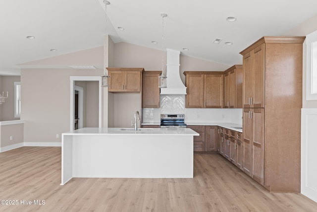 kitchen with a sink, premium range hood, vaulted ceiling, and electric stove