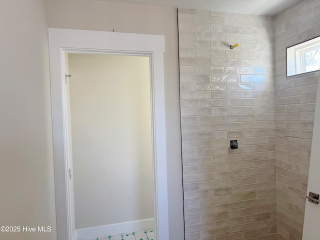 bathroom with tiled shower and baseboards