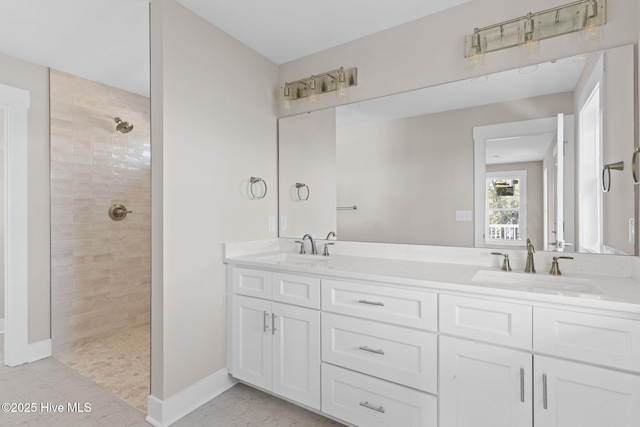 bathroom with a sink, a walk in shower, baseboards, and double vanity