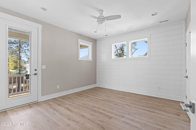 empty room with visible vents, light wood-style flooring, ceiling fan, and a healthy amount of sunlight
