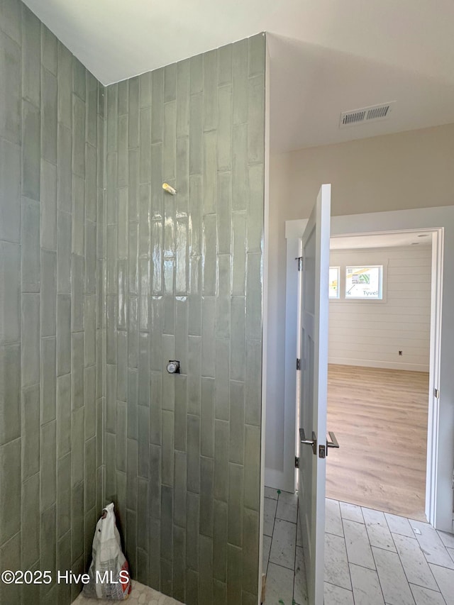 bathroom featuring visible vents, tiled shower, and wood finished floors