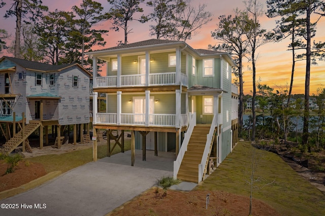 view of front facade featuring covered porch, a balcony, driveway, stairway, and a carport