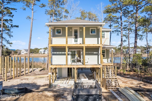 view of front of property featuring a shingled roof, a water view, a balcony, and stairs